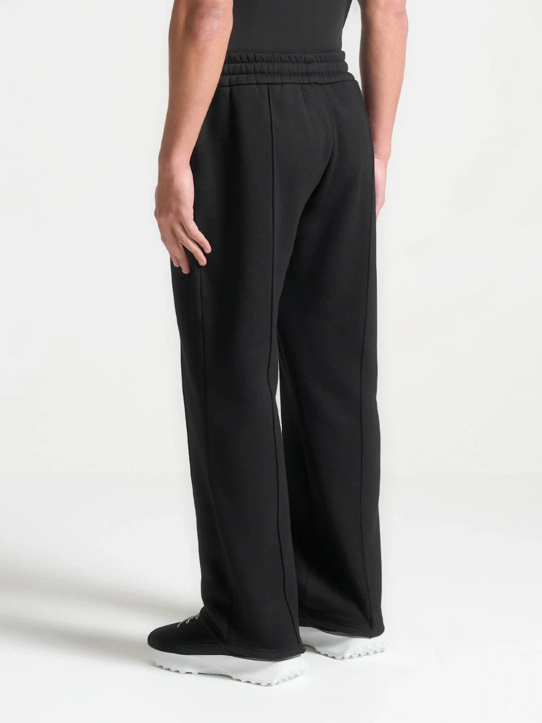 Person wearing black wide-leg pants on a white background