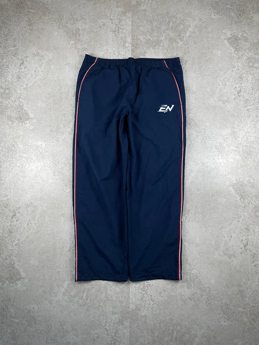 Navy blue athletic pants with a logo on a grey concrete surface