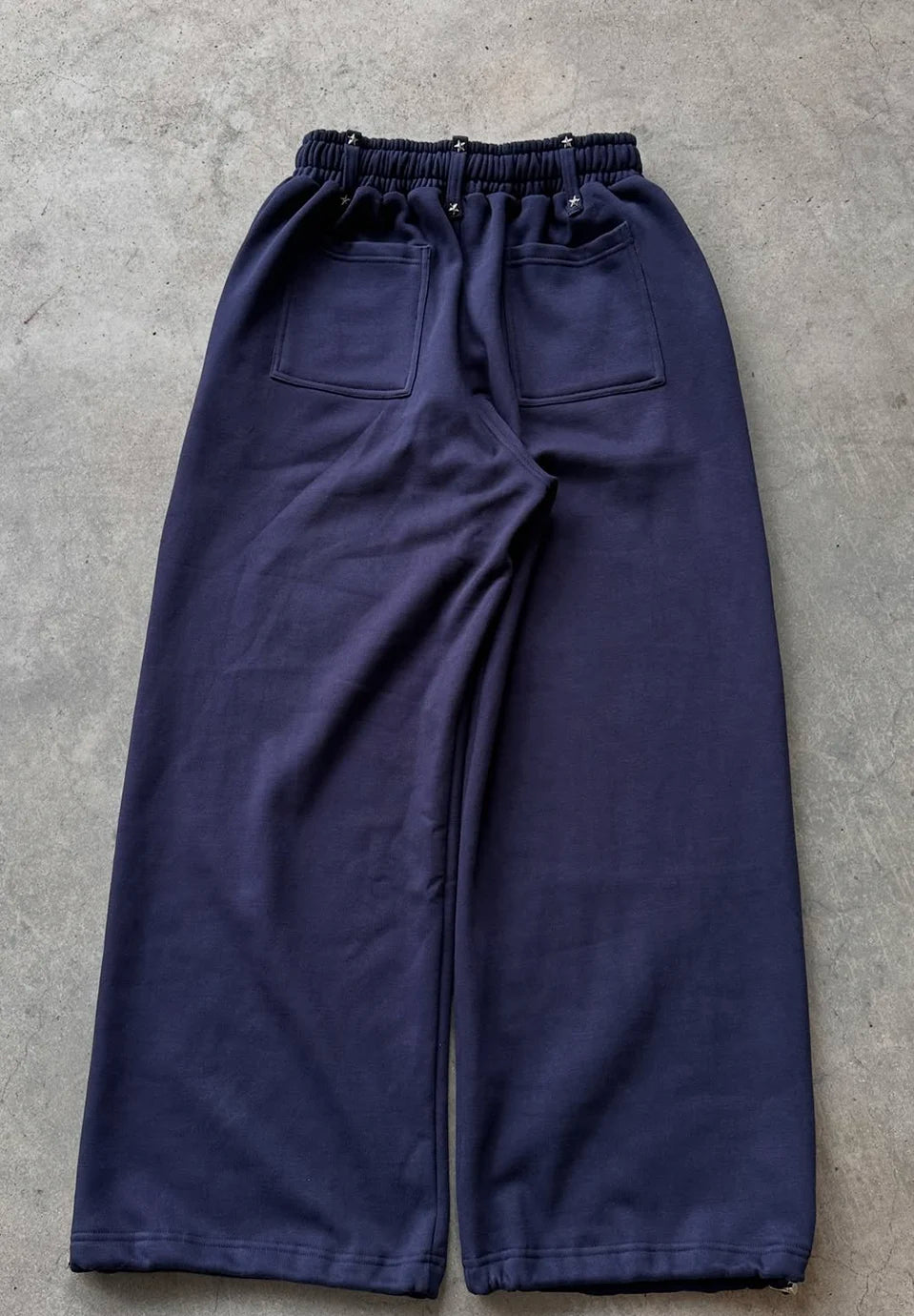 A pair of dark navy wide-leg sweatpants with an elastic waistband and two large patch pockets