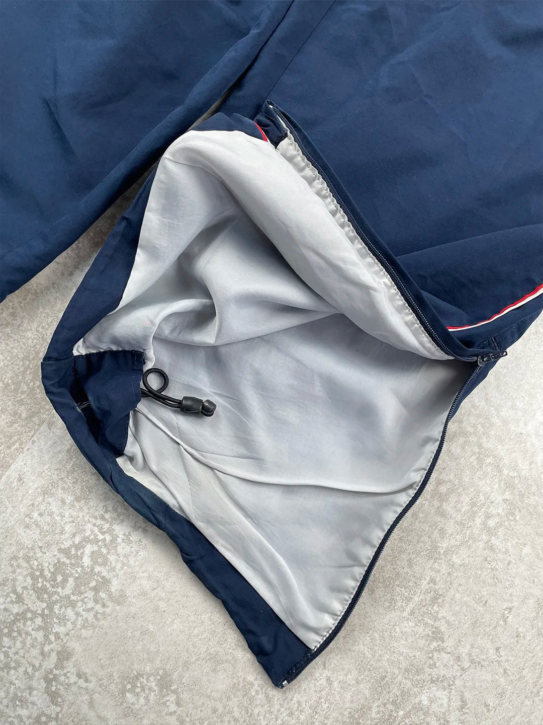 Close-up of a navy blue jacket with white lining on a light grey surface