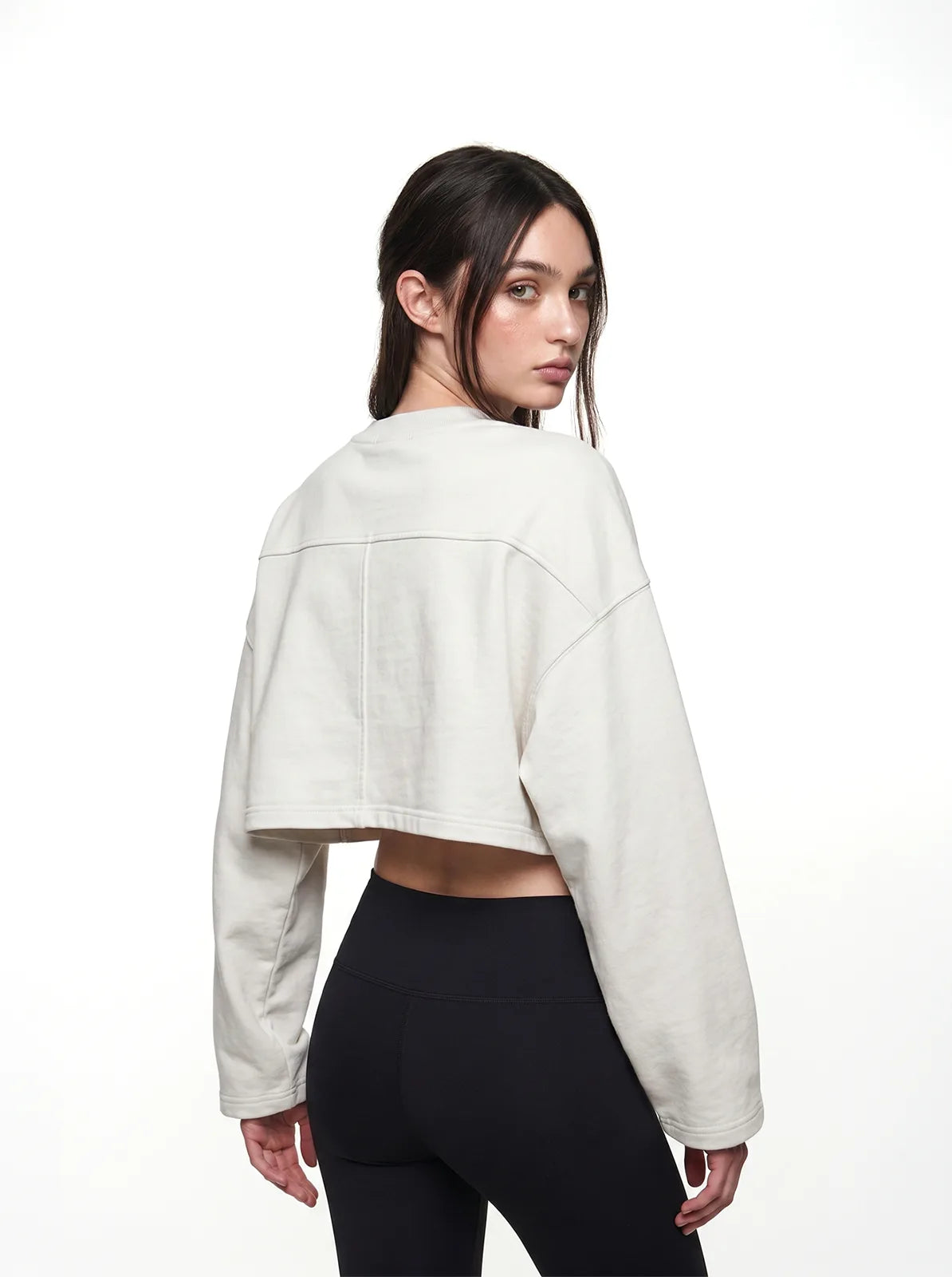 Woman wearing a white cropped t-shirt and black leggings on a white background