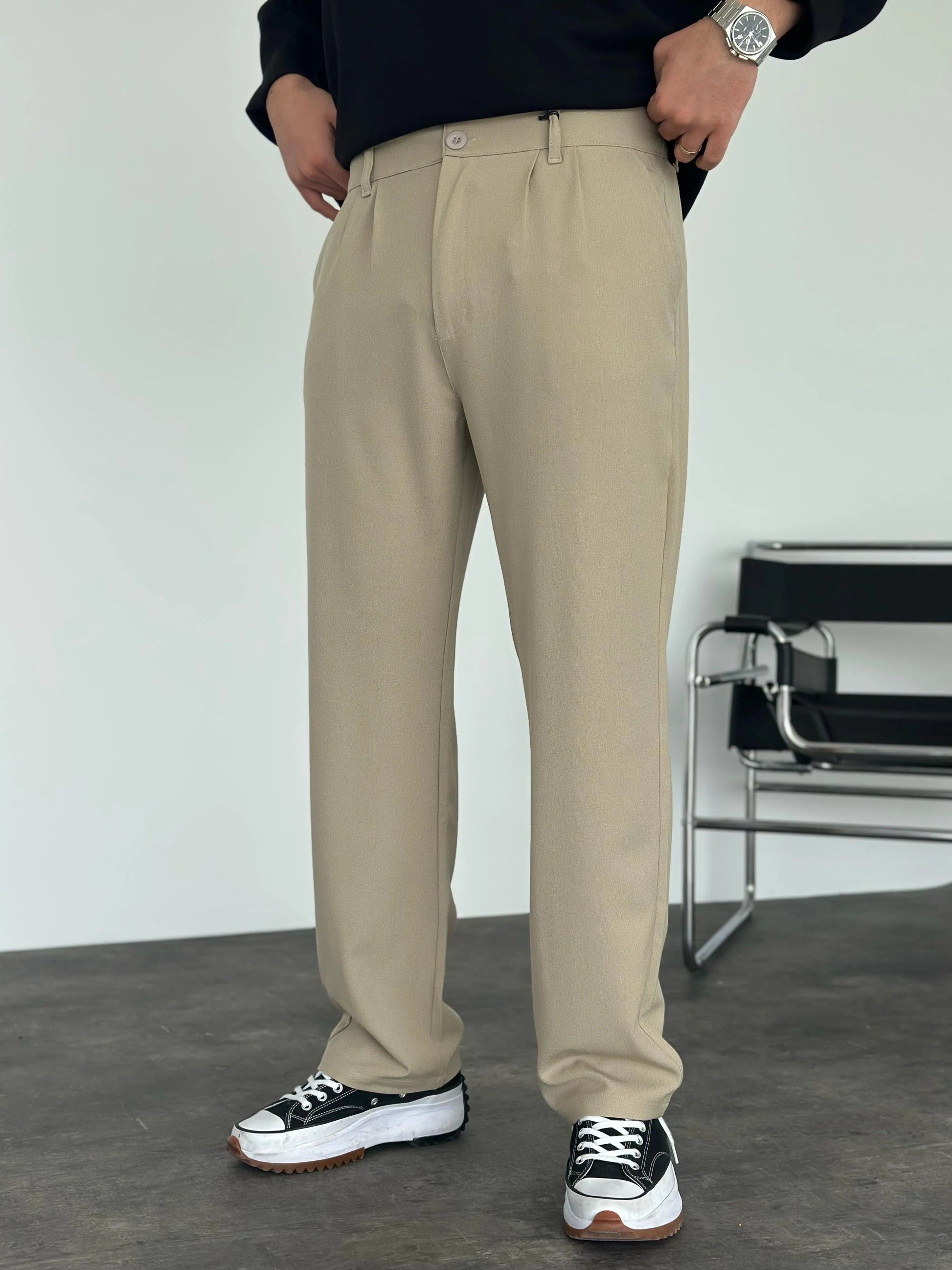 Person wearing beige pleated office pants 