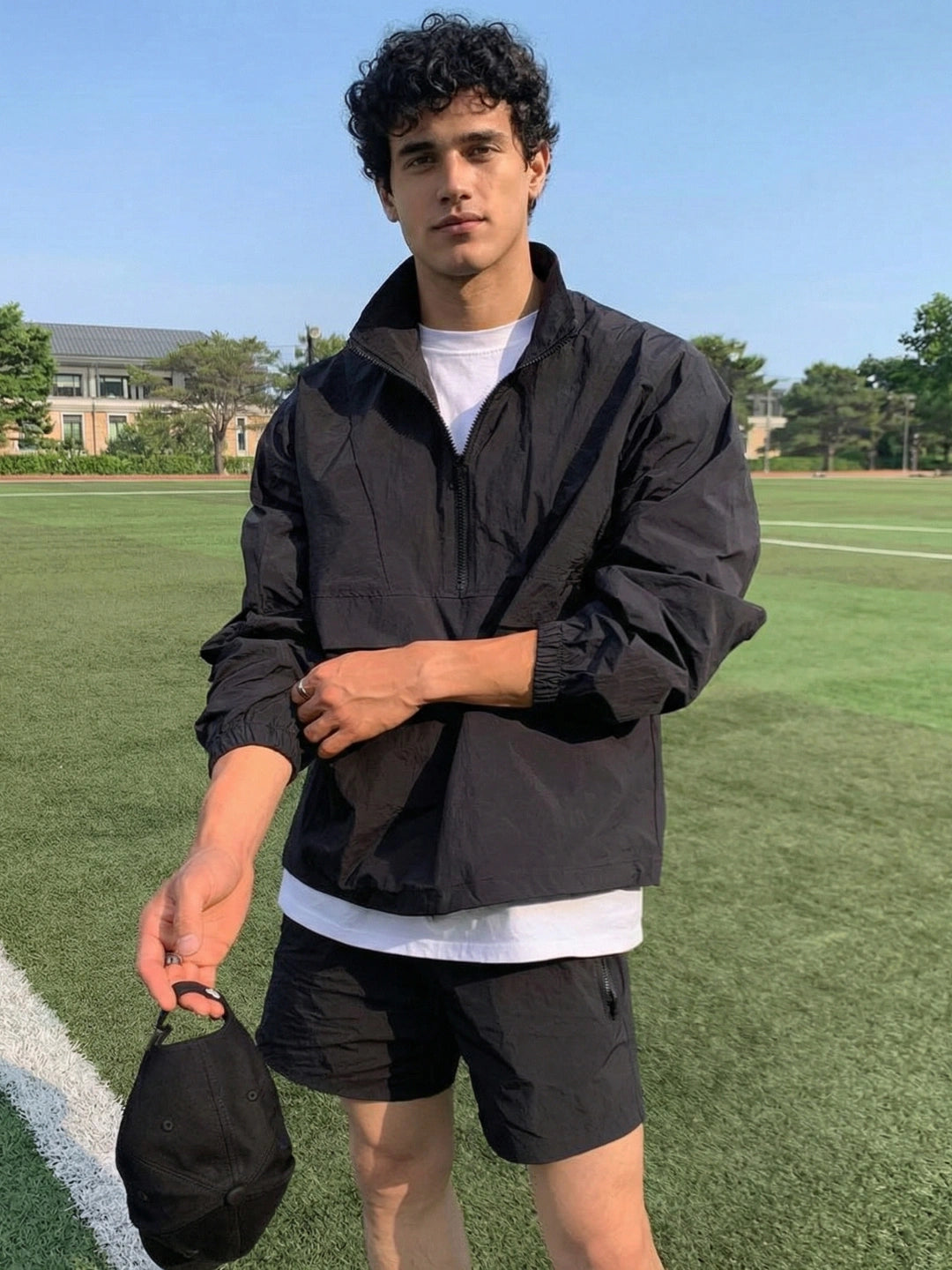 Person wearing a black jacket and shorts on a grassy field