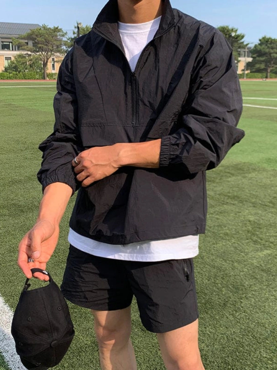 Person wearing a black jacket and shorts on a grassy field