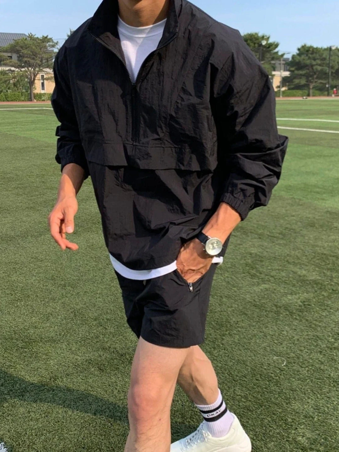 Person wearing a black jacket and shorts on a grassy field