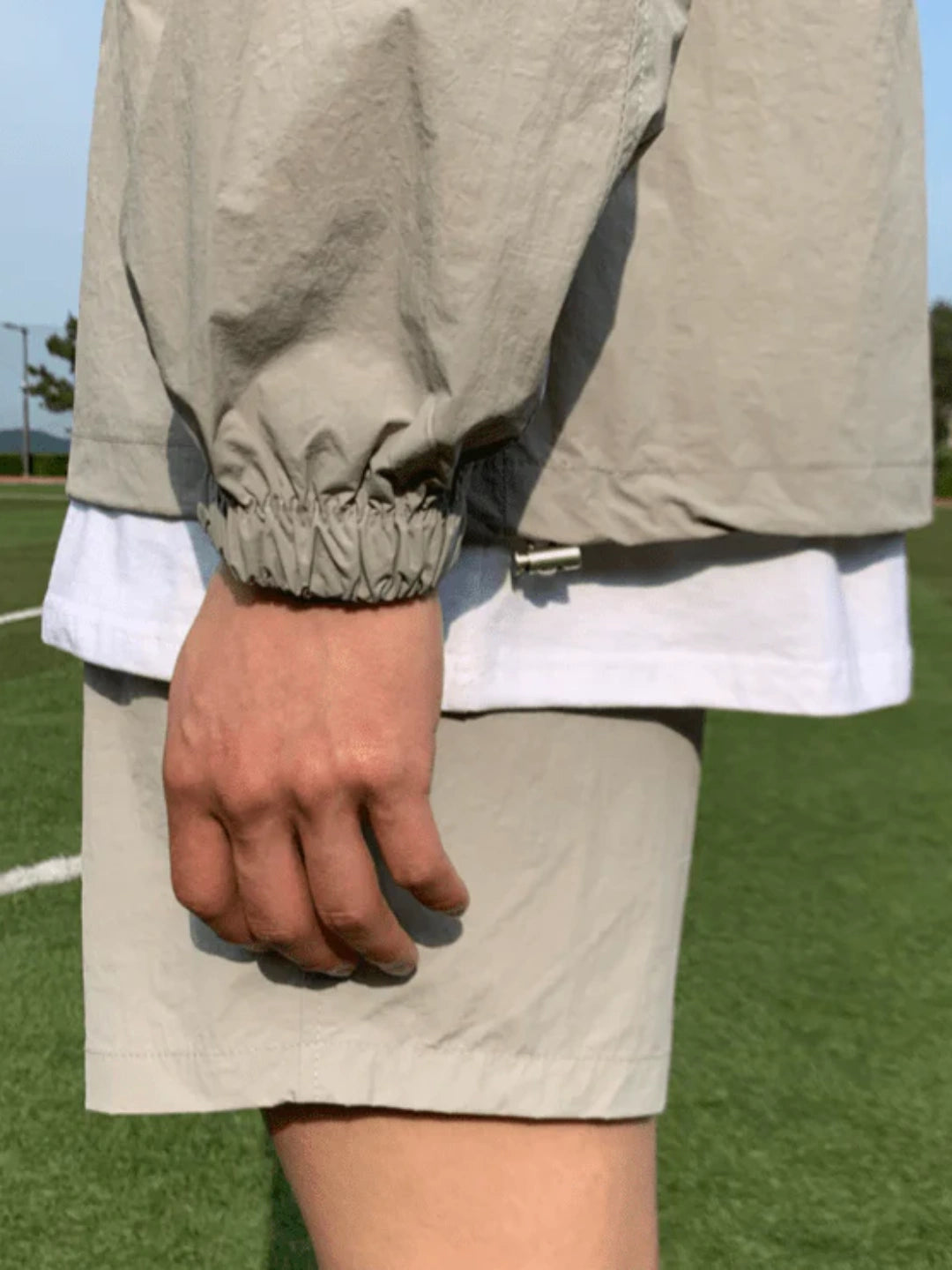Person wearing a beige jacket and shorts on a grassy field