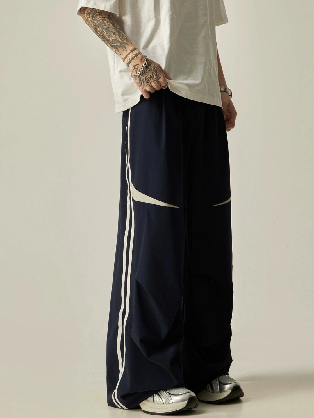 Person wearing navy pants with white stripes on a plain background