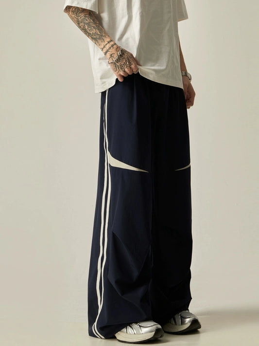 Person wearing navy pants with white stripes on a plain background