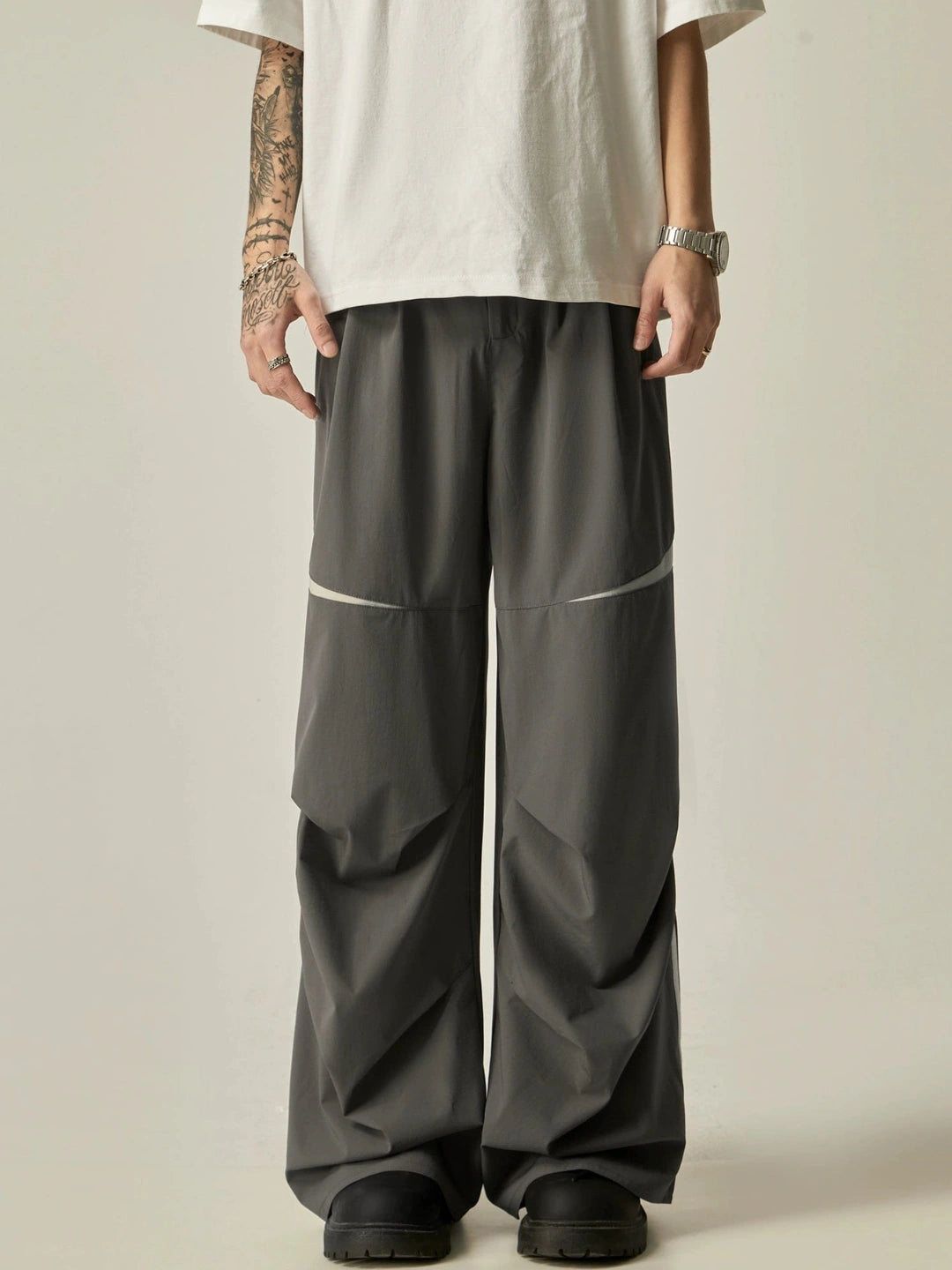 Person wearing dark grey wide-leg pants with a plain background