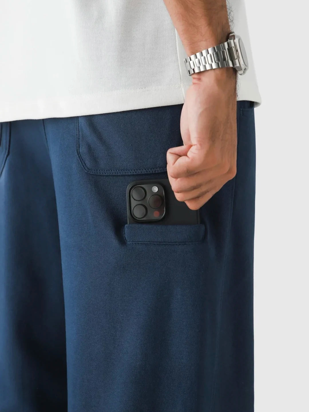 Person wearing navy pants with a phone in the pocket, white background