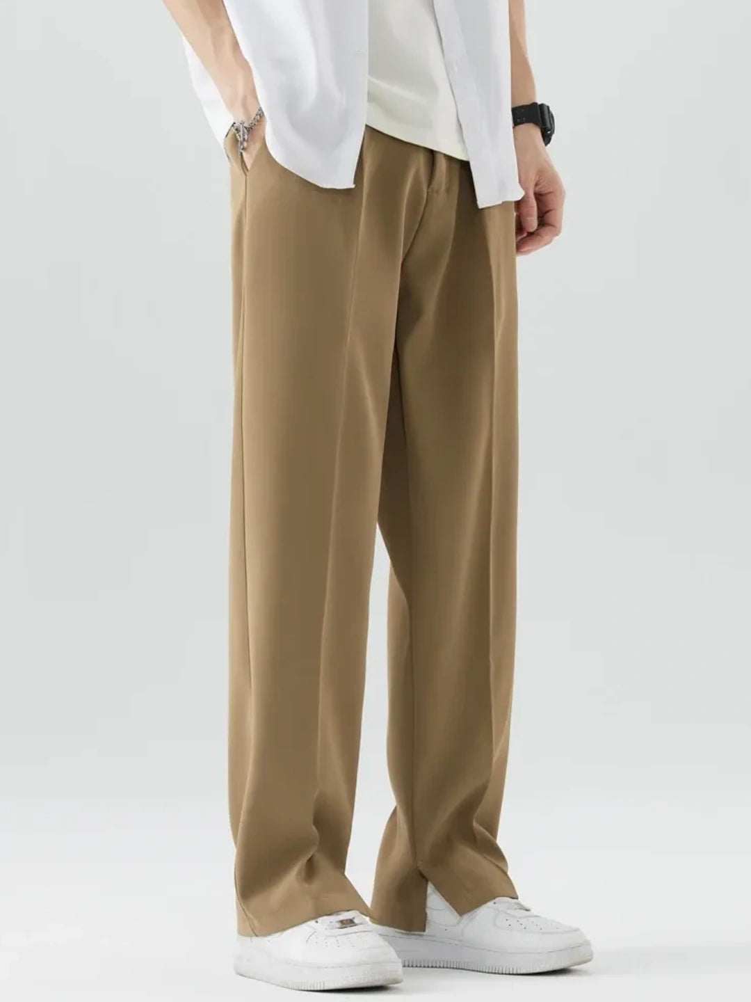 Person wearing brown pants and a white shirt on a plain background