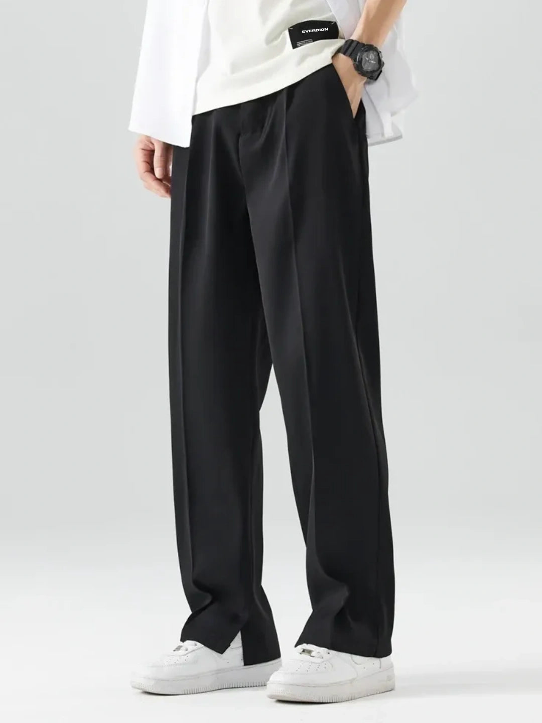 Person wearing black wide-leg pants with a white shirt on a light grey background