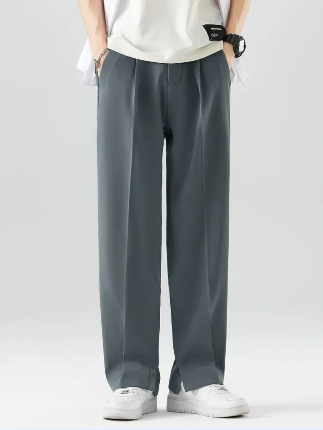 Person wearing grey pants and white shoes on a plain background