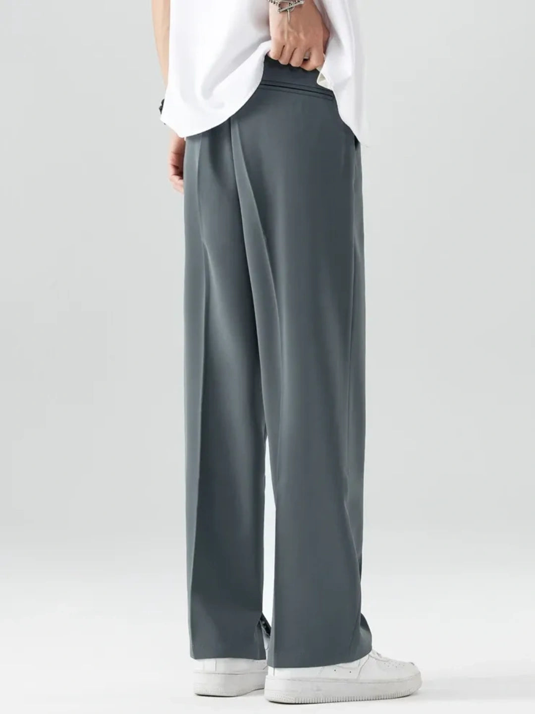 Grey pants worn with a white shirt on a plain background