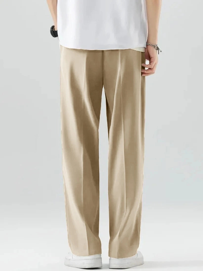 Person wearing beige pants and a white shirt on a plain background