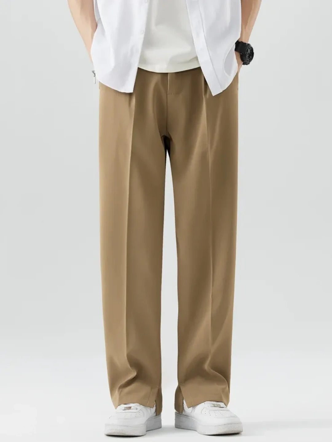 Person wearing beige pants and a white shirt on a plain background