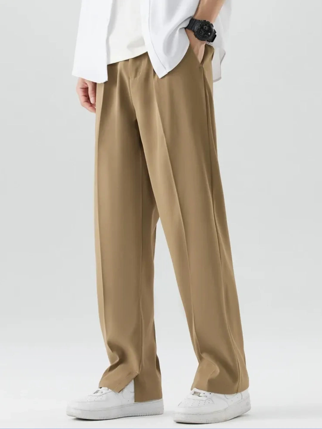 Person wearing beige pants and a white shirt on a plain background