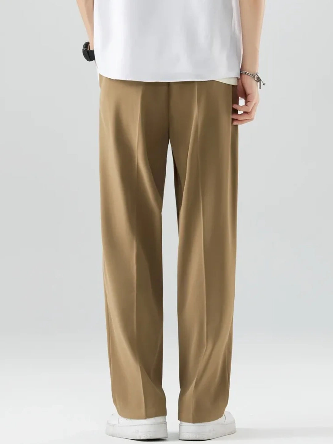 Person wearing beige pants and a white shirt on a plain background