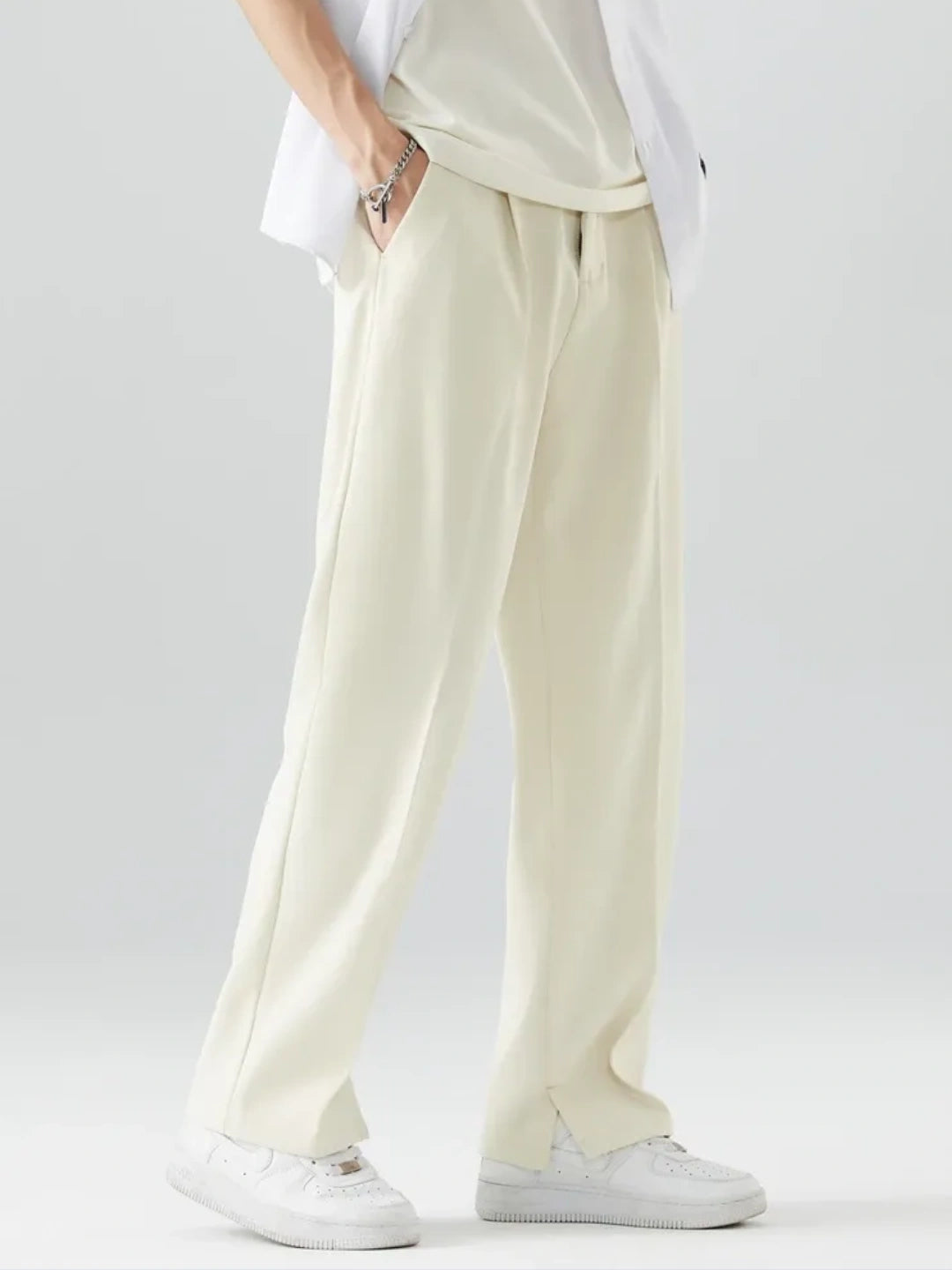 Person wearing light-colored pants and a white shirt on a plain background