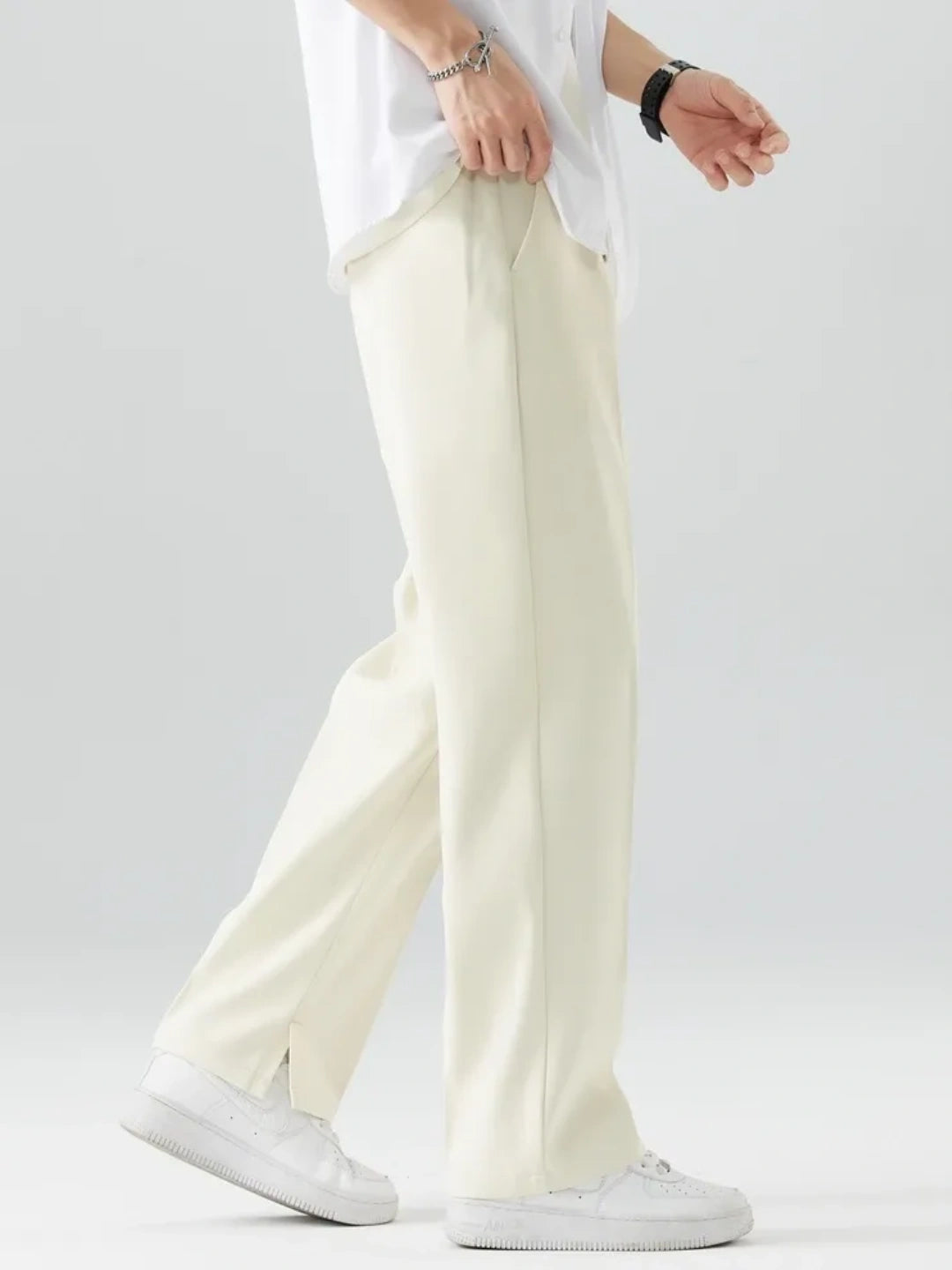Person wearing light-colored pants and a white shirt on a plain background