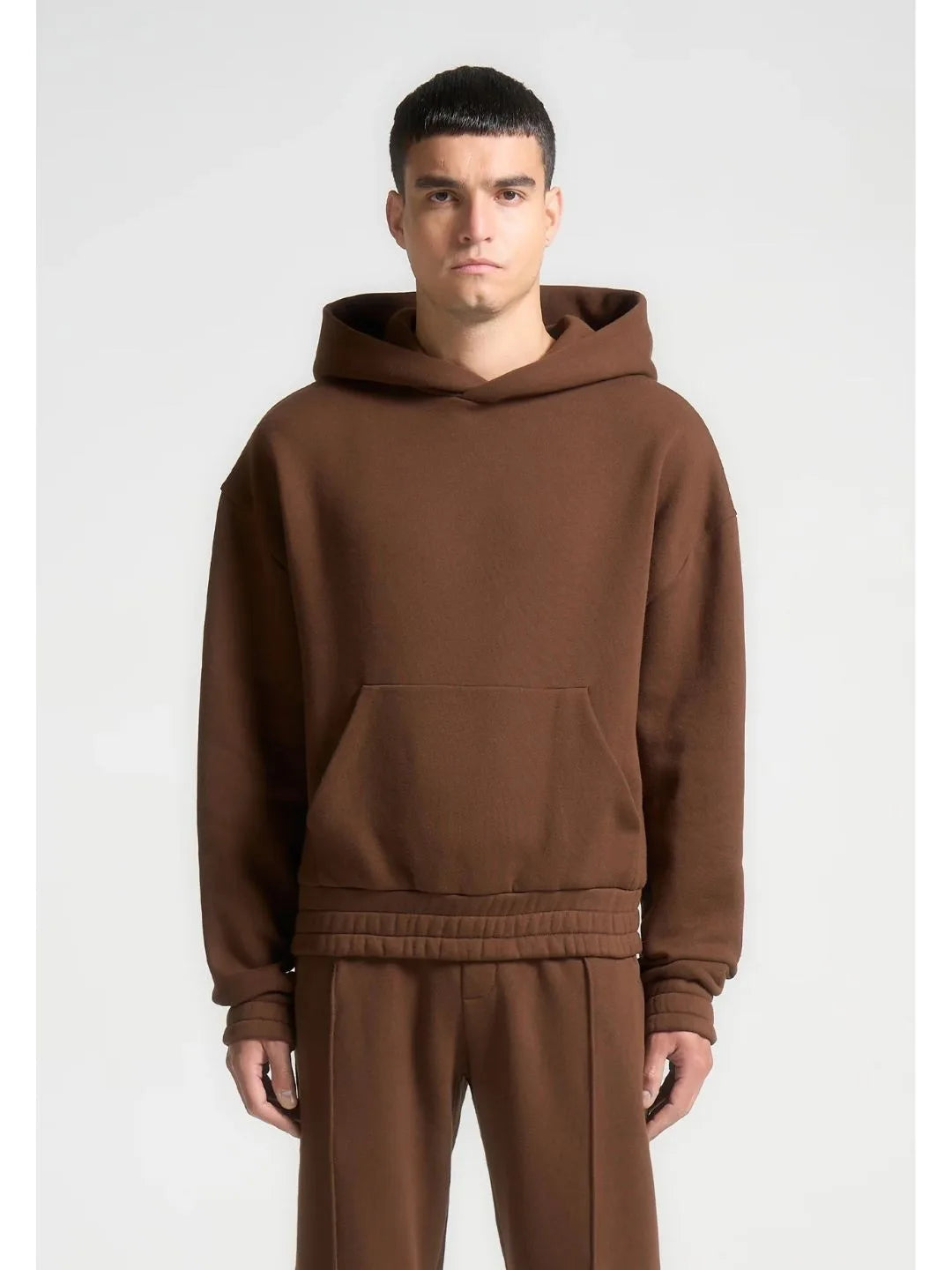 Man wearing a brown hoodie and pants on a white background