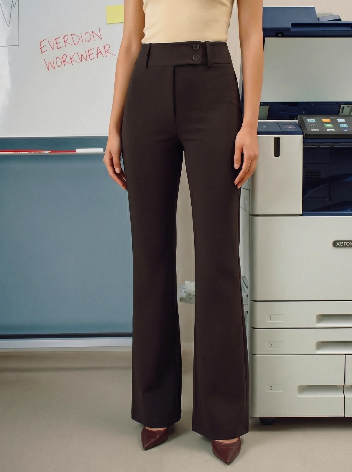 Person wearing brown pants standing in an office setting with a printer in the background.