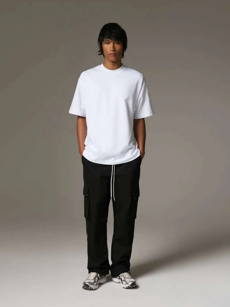 Person wearing a white t-shirt and black cargo pants on a grey background