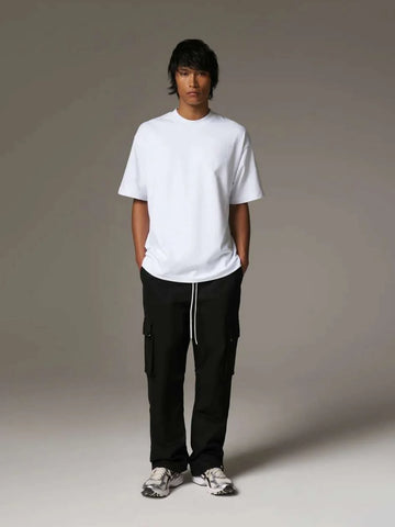 Person wearing a white t-shirt and black cargo pants on a grey background