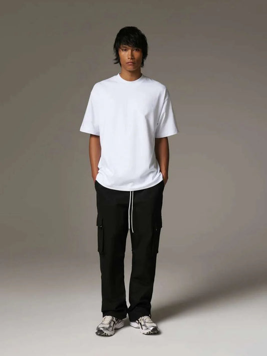 Person wearing a white t-shirt and black cargo pants on a grey background