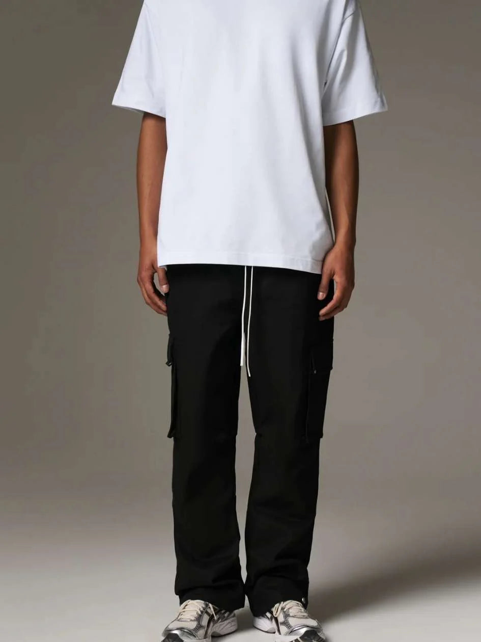 Person wearing a white oversized t-shirt and black cargo pants on a plain background