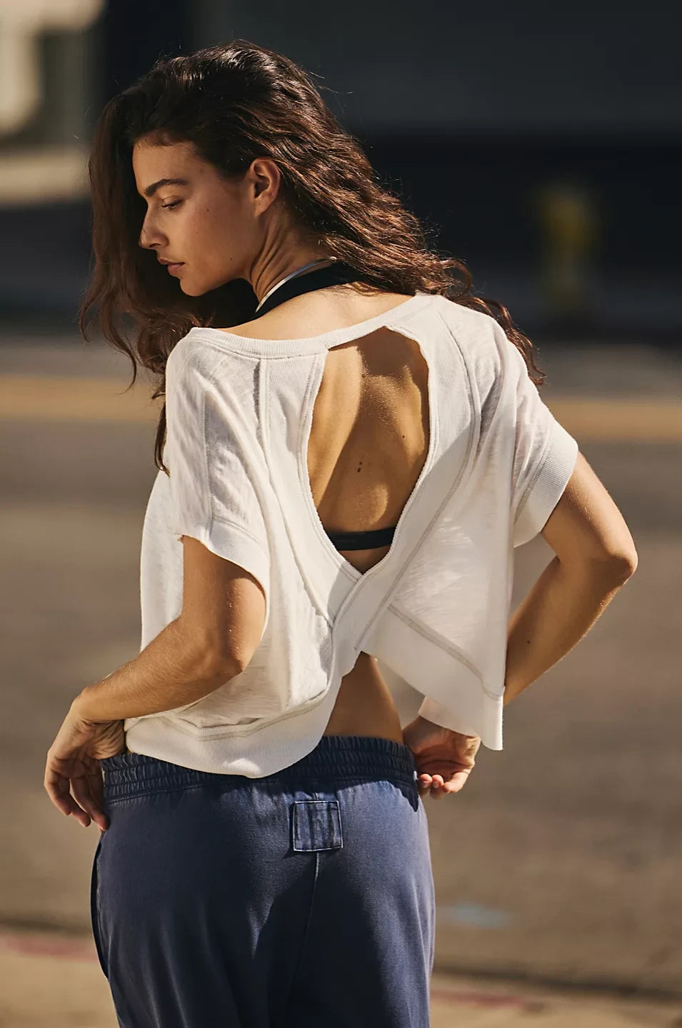 Woman wearing a white open-back top and dark pants outdoors