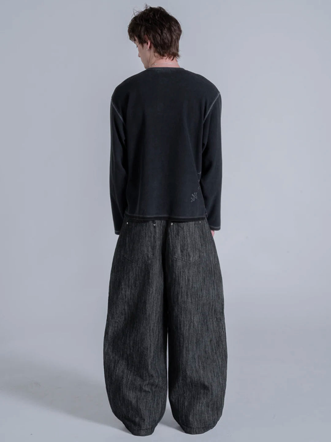 A model wearing a black long-sleeve t-shirt and very wide-leg dark grey denim pants