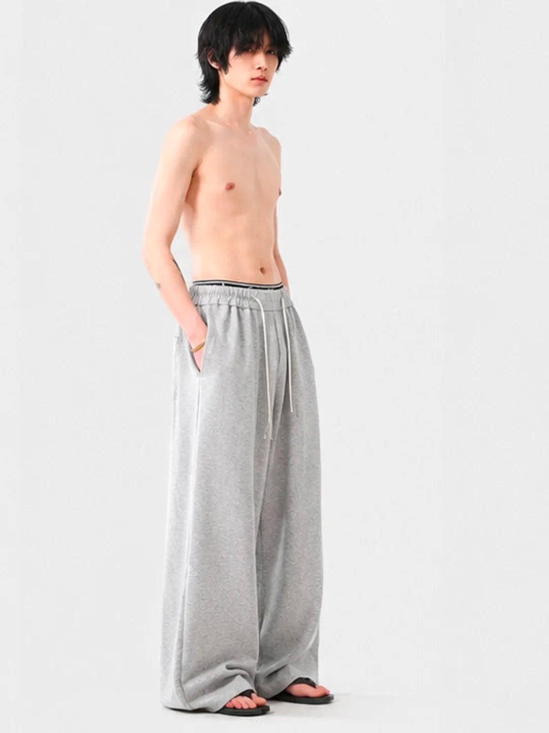Person wearing grey wide-leg sweatpants on a white background