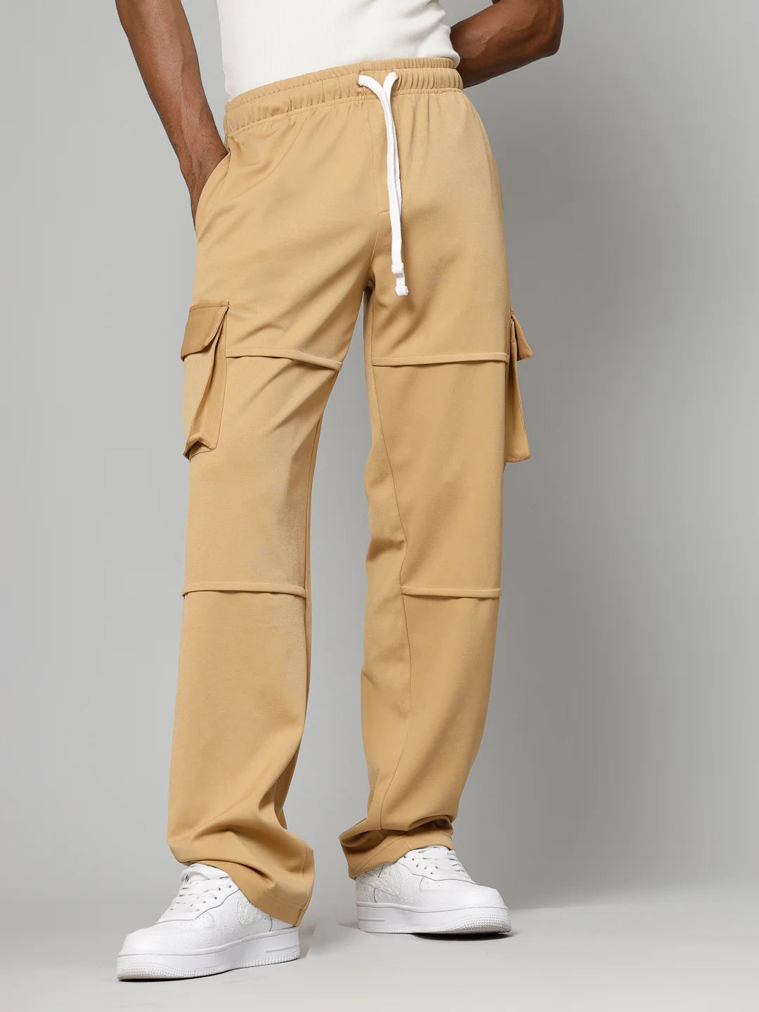 Beige cargo pants worn by a person on a grey background