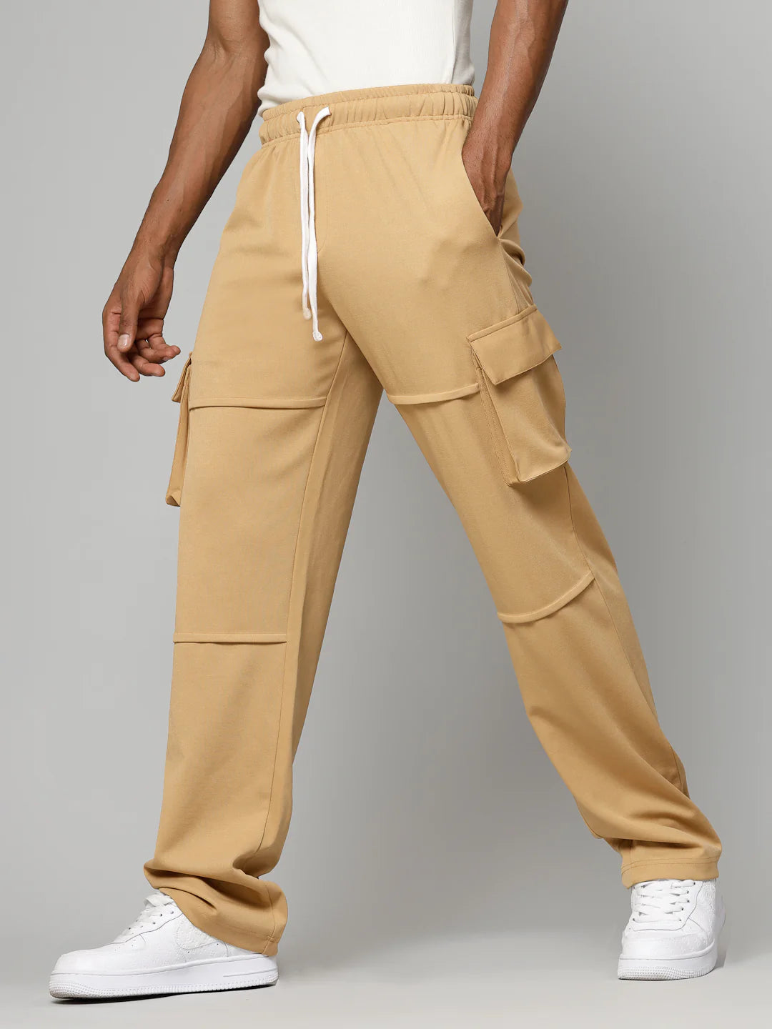 Person wearing beige cargo pants with a grey background