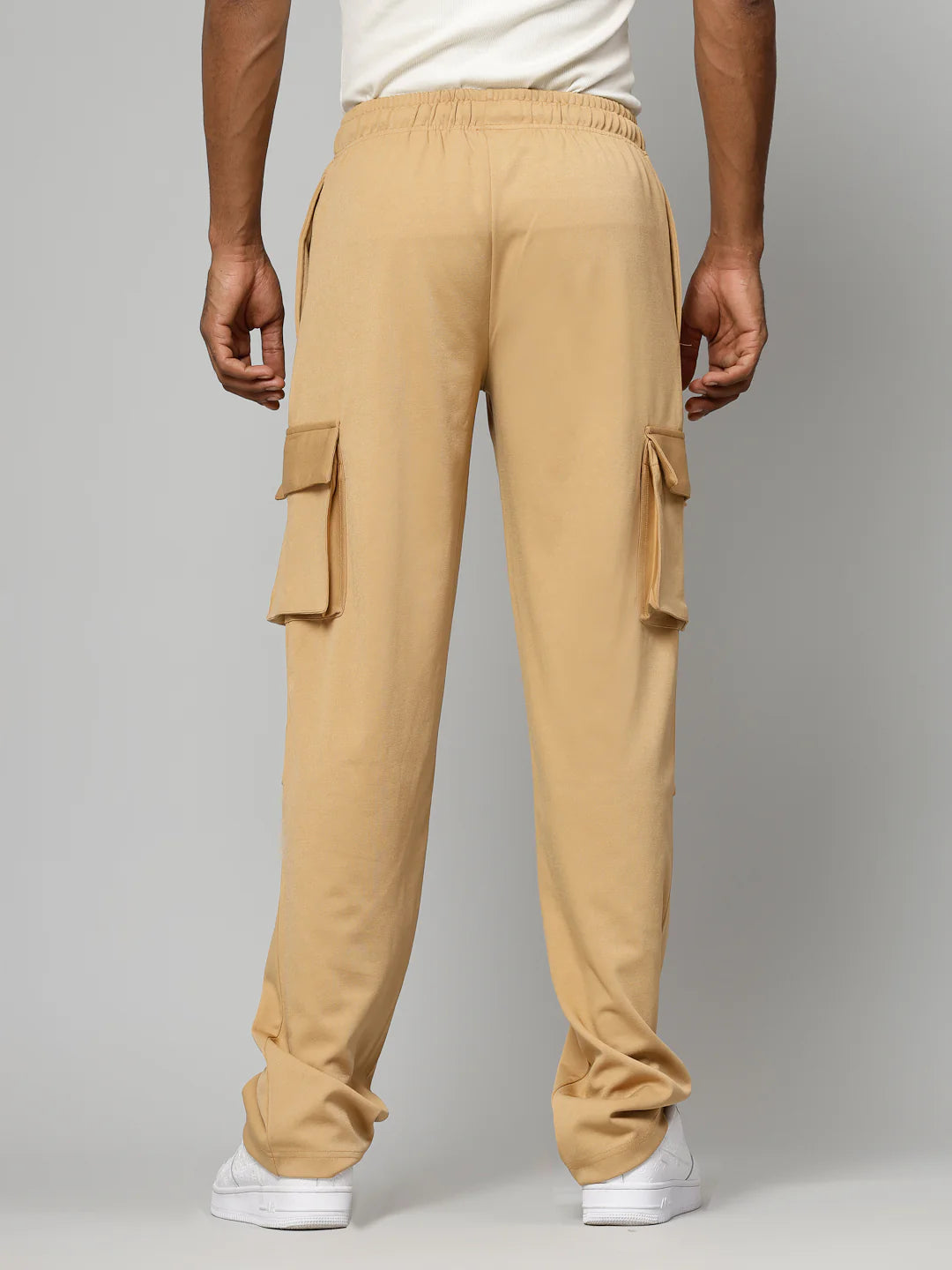 Beige cargo pants worn by a person on a grey background
