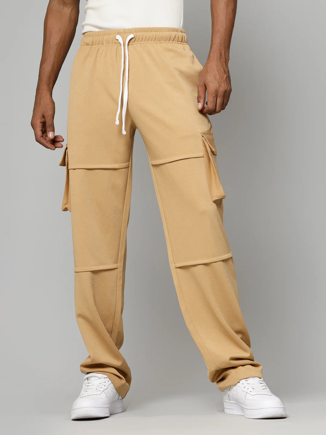 Tan cargo pants worn by a person on a grey background