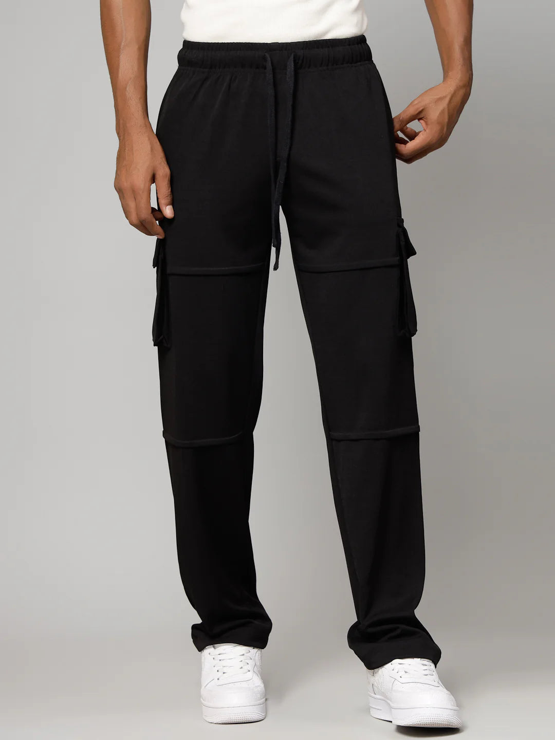 Person wearing black cargo pants on a grey background