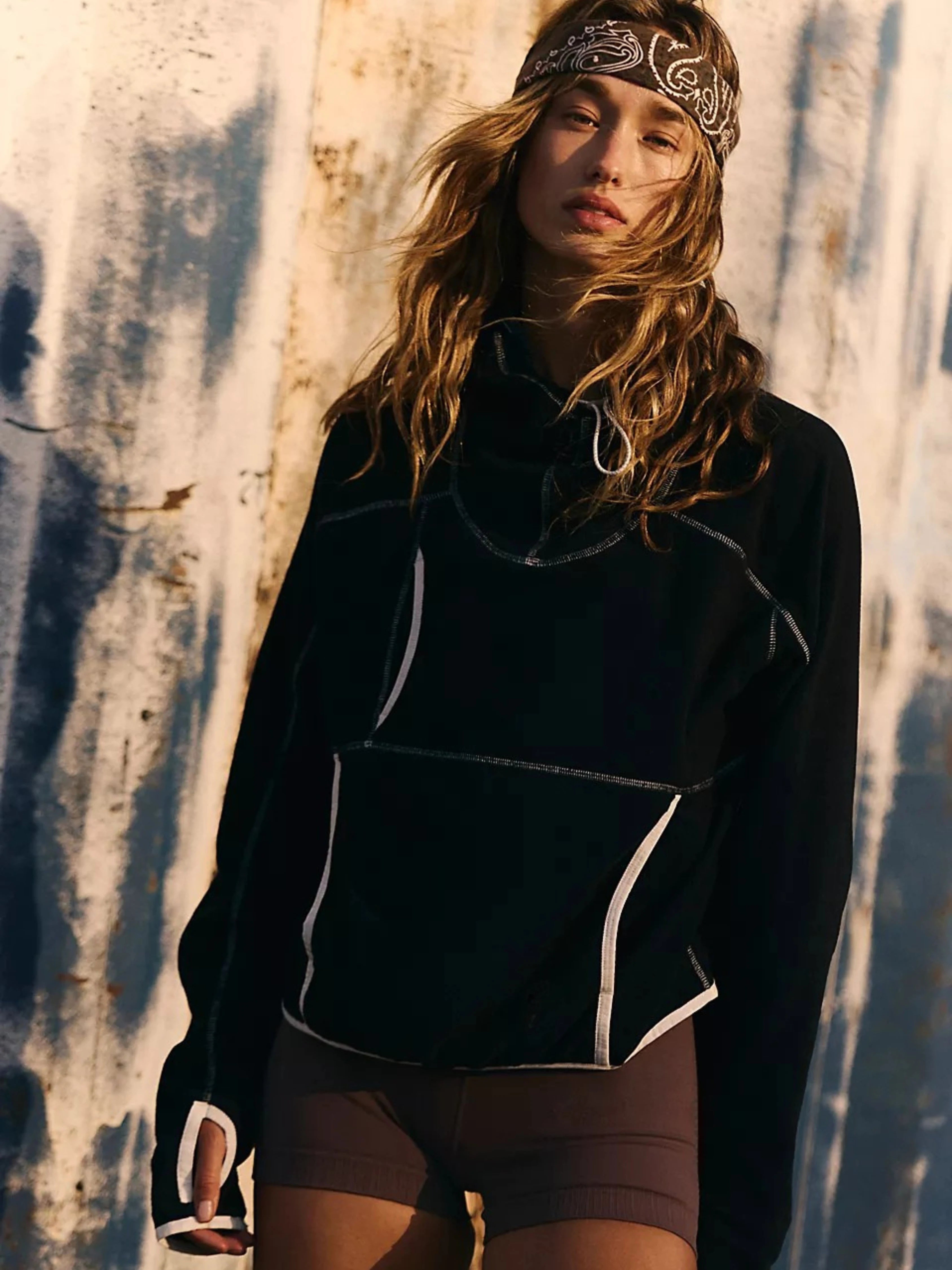 Person wearing a black jacket with white accents against a textured wall.