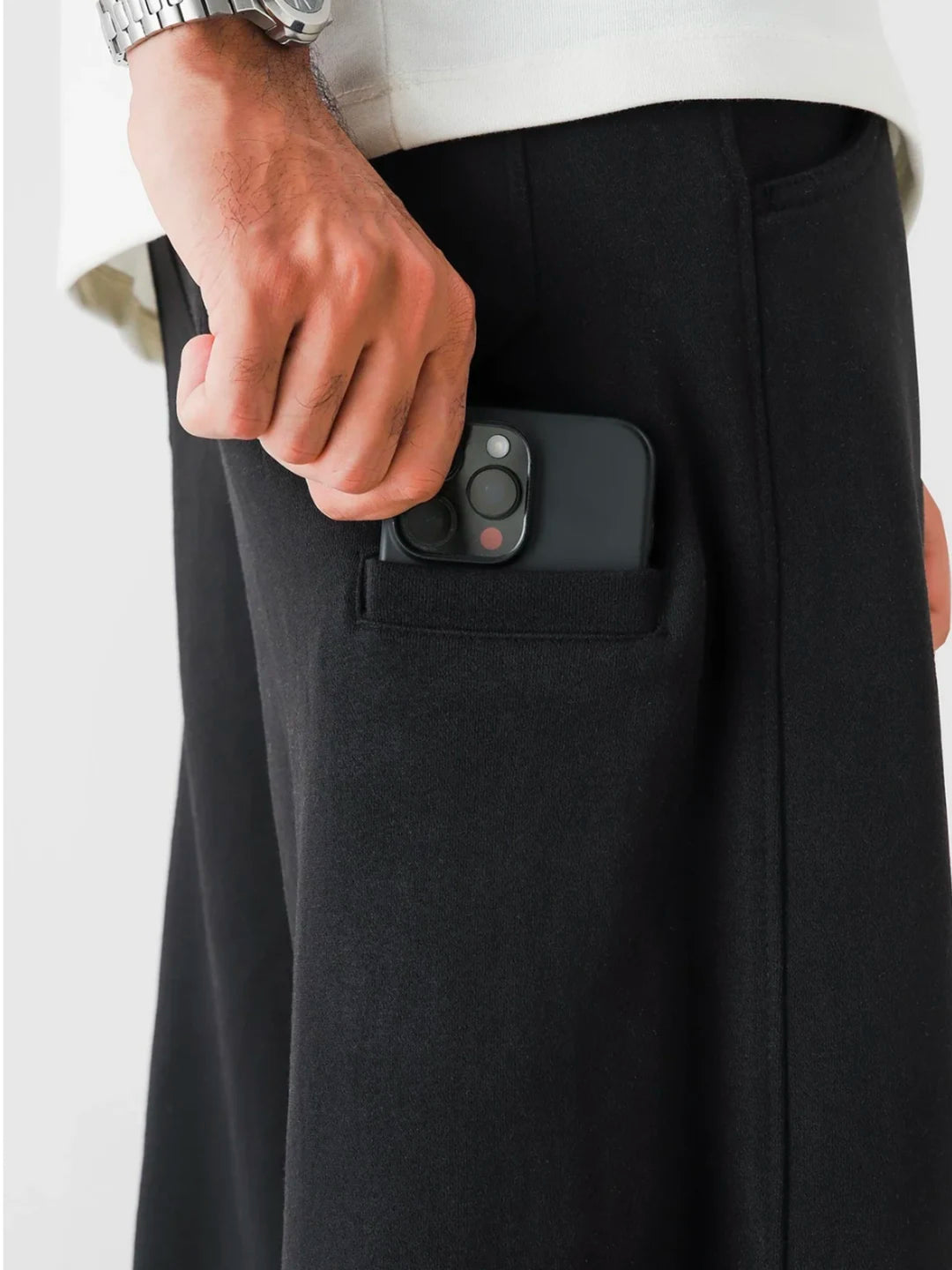 Person wearing a black phone case with a camera lens sticking out of their pocket.