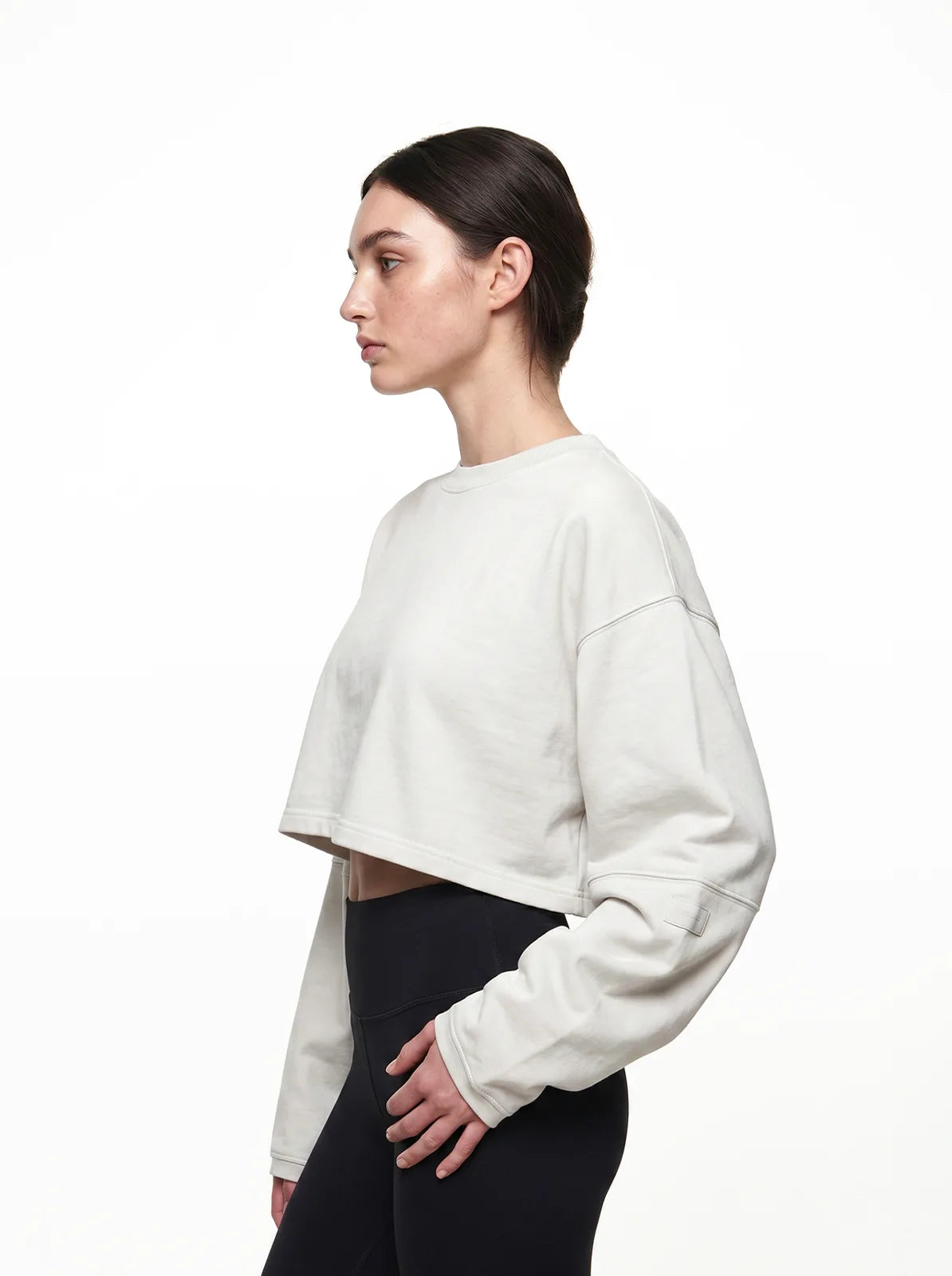 Woman wearing a white cropped t-shirt and black pants on a white background