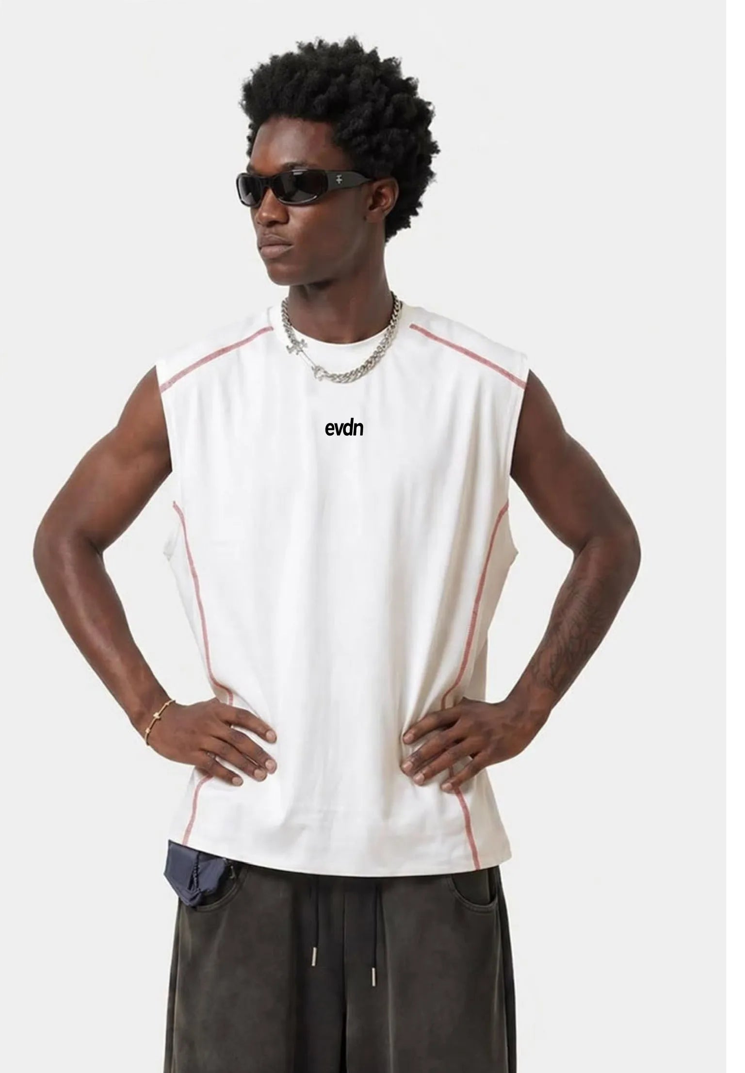 Man wearing a sleeveless white shirt with red accents and sunglasses on a white background