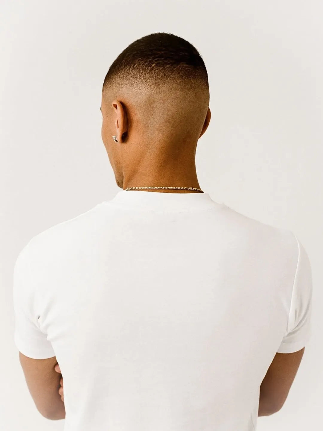 Person wearing a white fitted t-shirt on a plain background