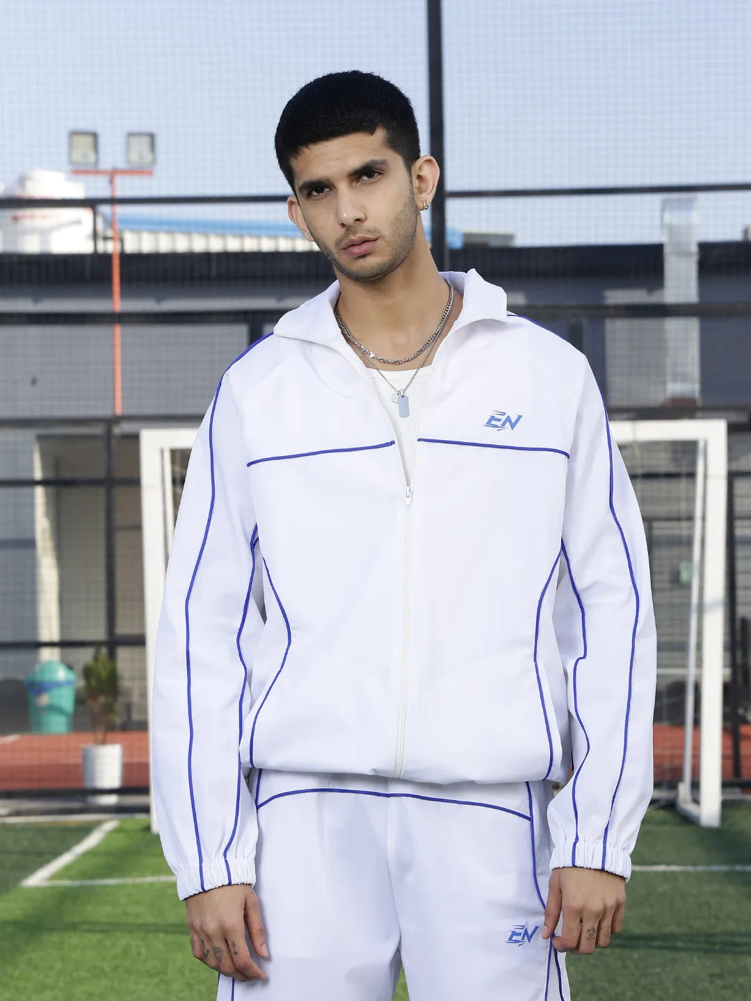 Person wearing a white sports jacket with blue accents on a sports field.