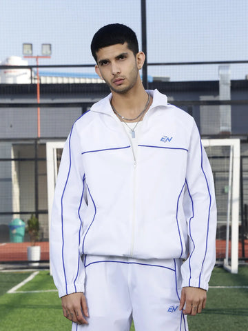 Person wearing a white sports jacket with blue accents on a sports field.