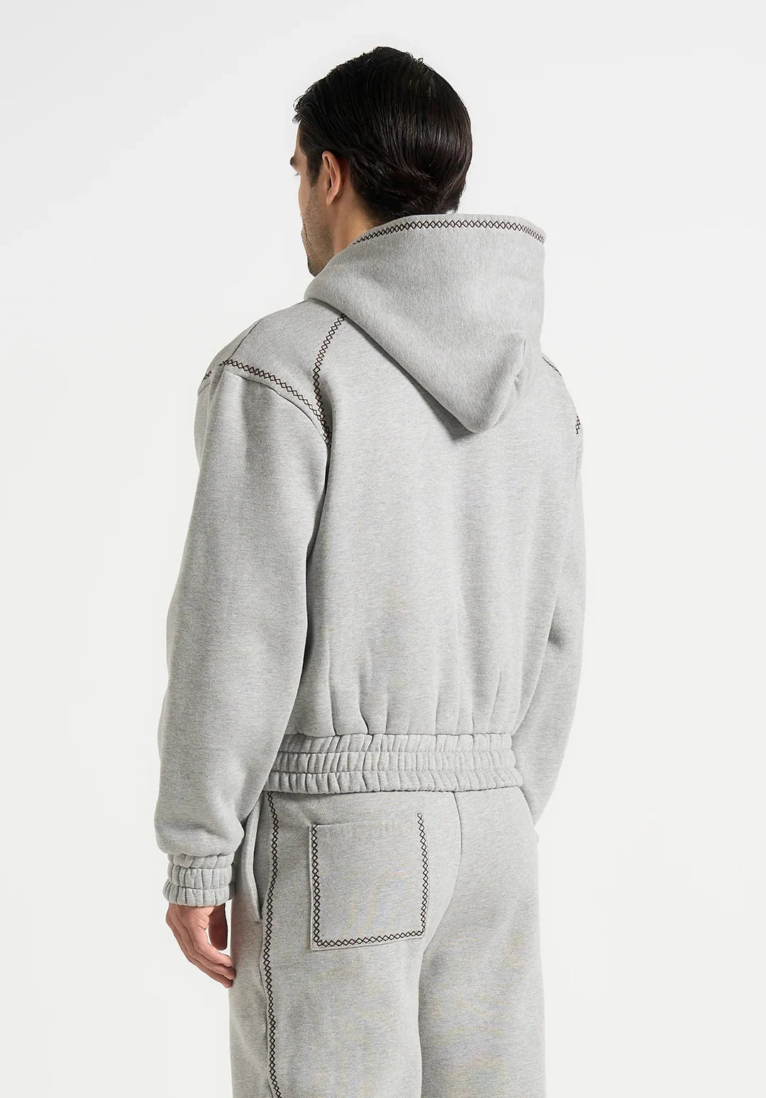 Person wearing a gray tracksuit with a hood on a white background