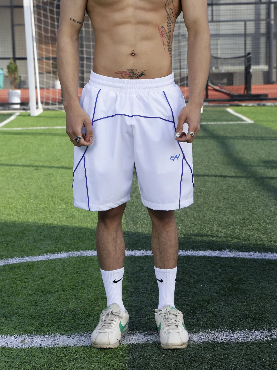 Person wearing white shorts with a logo on a sports field