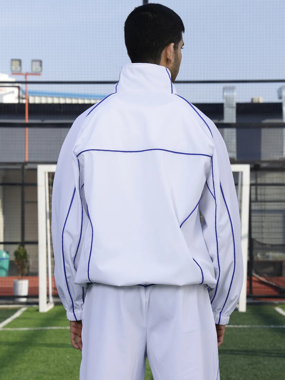 Person wearing a white sports jacket  with purple accents on a sports field.