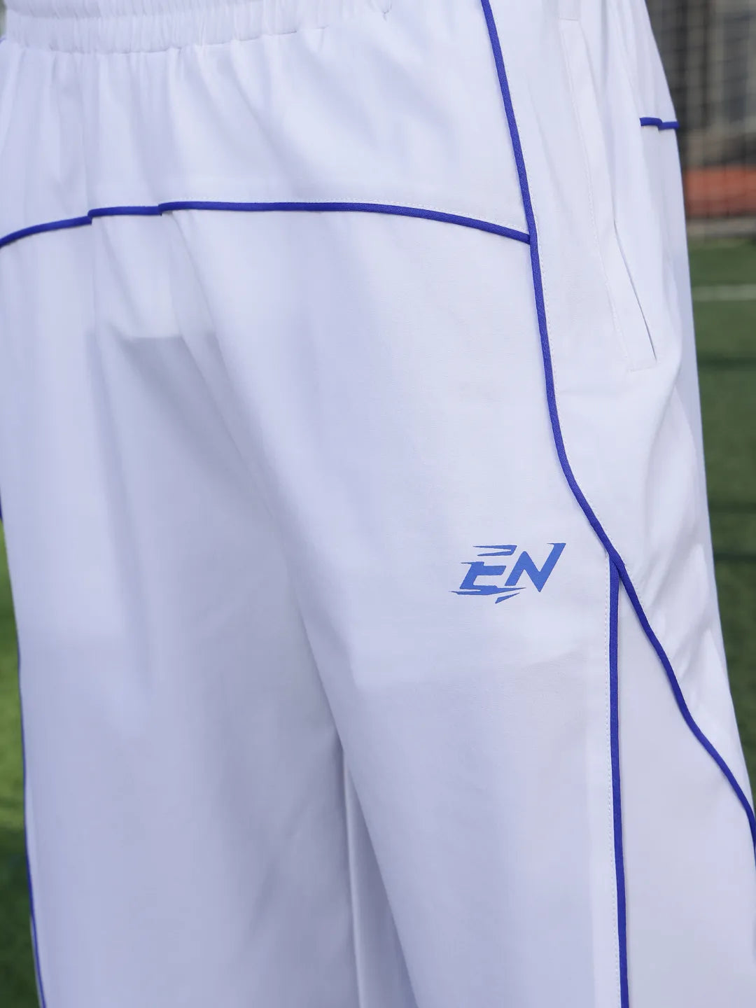 White pants with blue accents and a logo on a grassy field