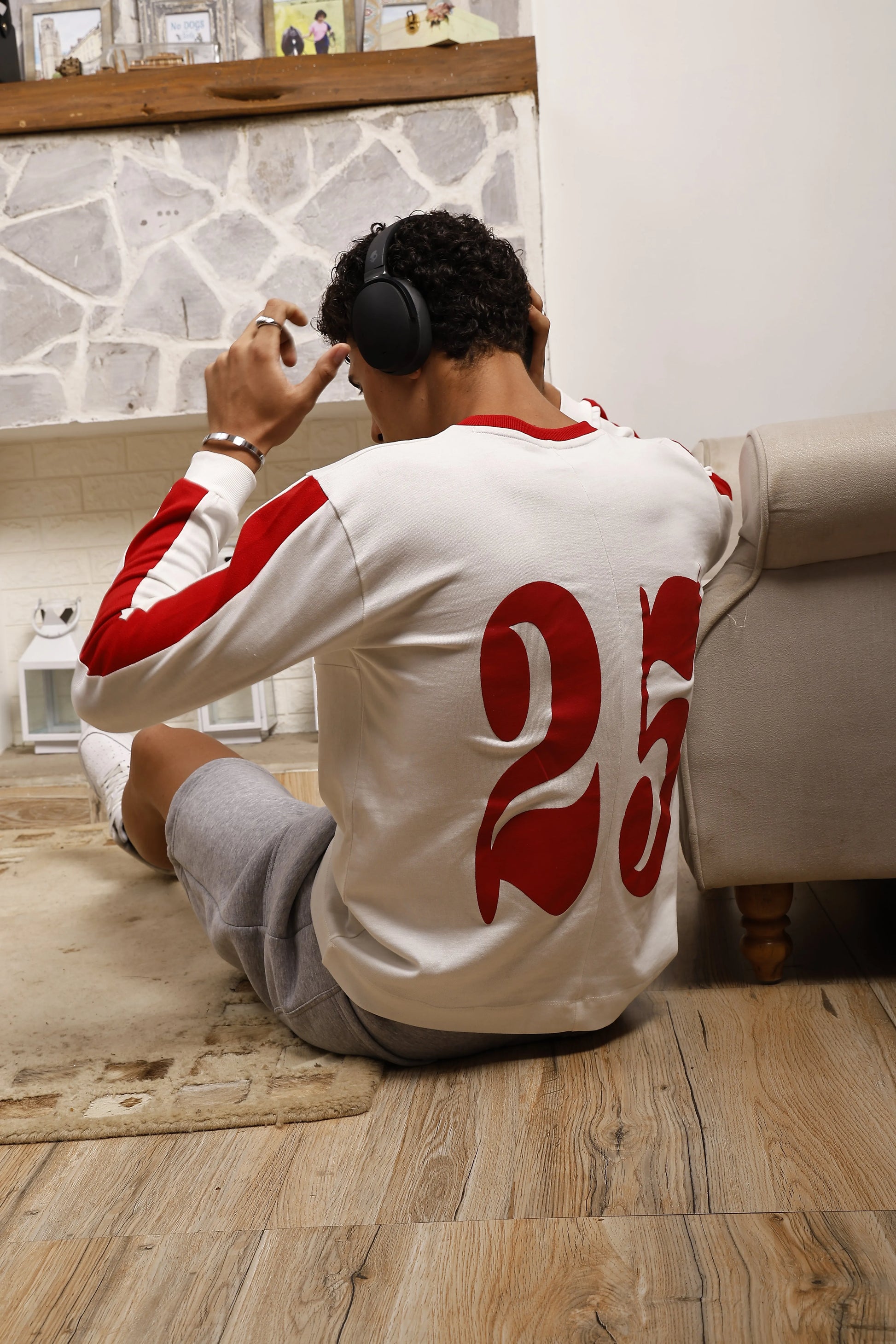 Person sitting on the floor wearing a white and red sports jersey with the number 25.